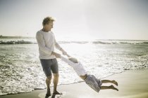 Père balançant fils sur la plage — Photo de stock