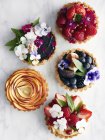 Top view of various tarts with fruit and flowers — Stock Photo