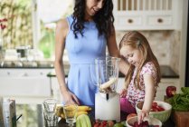Mother and daughter making smoothies together — Stock Photo