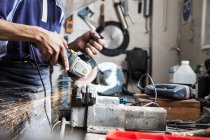 Mid section of young man using angle grinder in repair workshop — Stock Photo