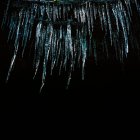 Baixo ângulo de visão de icicles em fundo preto, close-up — Fotografia de Stock