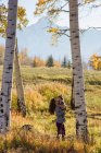 Mother holding toddler amongst autumnal silver birch trees — Stock Photo