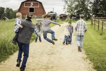 Полноразмерный вид сзади многодетной семьи, идущей по колее на ферме — стоковое фото