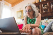 Woman on sofa using laptop at home — Stock Photo