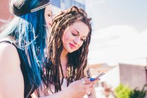 Duas jovens mulheres lendo textos de smartphones na propriedade de habitação urbana — Fotografia de Stock