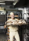 Счастливый пекарь кладет в духовку кусочек нарезанного хлеба — стоковое фото