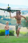 Padre e figlio che pilotano aerei telecomandati, all'aperto — Foto stock