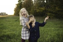 Schwester bedeckt lächelnd Bruders Augen — Stockfoto