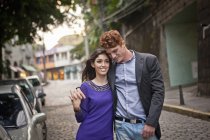 Couple walking along street, arms around each other, smiling — Stock Photo