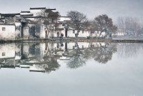 Immagine speculare di alberi spogli e case tradizionali sul lago, villaggio di Hongcun, provincia di Anhui, Cina — Foto stock