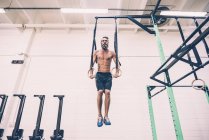 Young male cross trainer training on gymnastic rings — Stock Photo