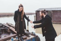 Man helping girlfriend from barge on canal waterfront — Stock Photo