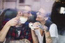 Vista a través de la ventana de la pareja en la cafetería cara a cara sonriendo - foto de stock
