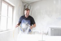 Людина розпилює фарбування деревини в приміщенні — стокове фото