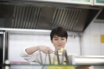 Jovem mulher preparando comida em loja de fast food — Fotografia de Stock