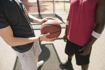 Mid section of two male basketball players with ball on basketball court — Stock Photo