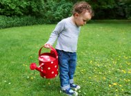 Kleinkind trägt Gießkanne — Stockfoto