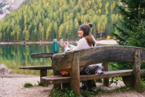 Femme se relaxant sur le banc du parc, Lago di Braies, Alpes Dolomites, Val di Braies, Tyrol du Sud, Italie — Photo de stock