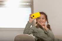 Menina brincando com telefone celular no sofá — Fotografia de Stock