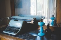 Винтажная пишущая машинка и масляные лампы на столе — стоковое фото