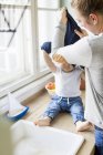 Frau zieht Baby-Sohn an Küchenspüle aus — Stockfoto