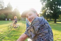 Портрет молодого человека, оглядывающегося через плечо в солнечном парке — стоковое фото