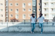 Identical male hipster twins chatting on apartment roof terrace — Stock Photo