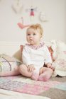 Porträt eines Babys, das neben Kissen sitzt — Stockfoto