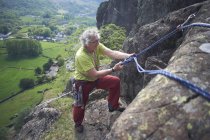Scalatore di roccia sulla parete di roccia che prepara la corda da arrampicata — Foto stock