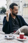 Homme adulte moyen fumant une cigarette au café sur le trottoir — Photo de stock