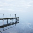 Ponte de madeira sobre lago imóvel refletindo na água — Fotografia de Stock