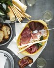 Top view of meal with dish of salumi and breadsticks — Stock Photo