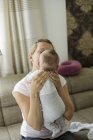 Madre apoyando a los hijos del bebé cabeza con manos - foto de stock