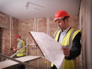 Architect with plans on building site — Stock Photo