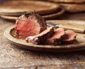 Fillet of beef with knife on wooden plate — Stock Photo