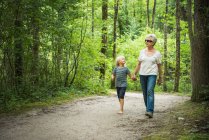 Grandmother and grandson walking in forest holding hands — Stock Photo