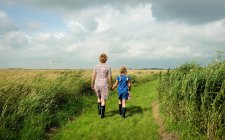Rear view of mother and daughter walking in field — Stock Photo