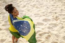 Oben Porträt einer jungen Frau in brasilianische Flagge gehüllt, Strand von Ipanema, Rio de Janeiro, Brasilien — Stockfoto