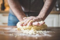 Abgeschnittenes Bild eines Mannes, der Teig in der Küche knetet — Stockfoto