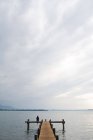 Femme assise sur une jetée au lac — Photo de stock