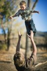 Padre lanzando joven hijo en el aire - foto de stock