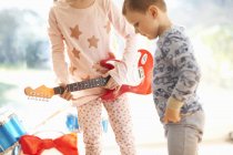 Chica y hermano jugando con la guitarra de juguete en el día de Navidad - foto de stock