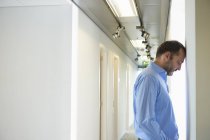 Mature man leaning head against wall in corridor — Stock Photo
