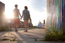 Young couple walking holding hands, rear view — Stock Photo