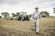 Agricoltore a piedi dal trattore e aratro in campo — Foto stock