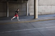 Young male runner running up city underpass — Stock Photo