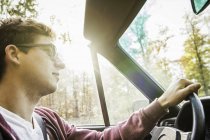 Junger Mann fährt Auto auf Landstraße — Stockfoto