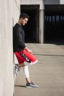 Young male runner leaning against underpass wall taking a break — Stock Photo