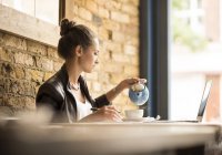 Junge Geschäftsfrau gießt Tee in Café ein — Stockfoto