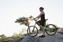 Чоловічий велосипедист стоїть на скелях — стокове фото